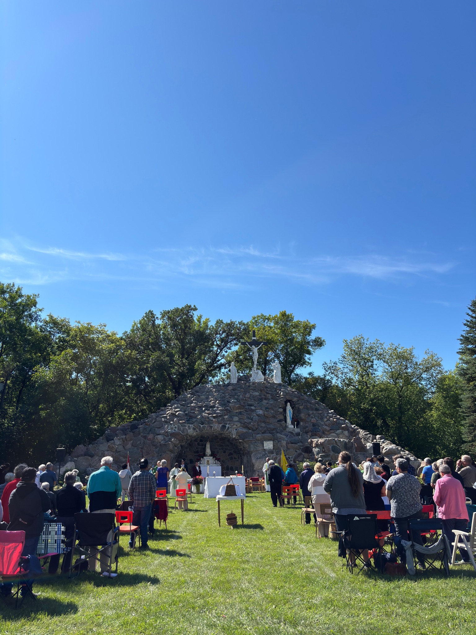 Large outdoor worship service at a stone grotto with the full Bethel congregation